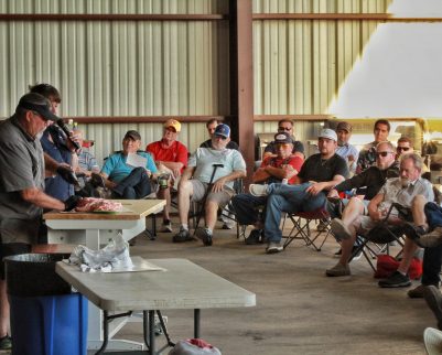 tony valentine preeing brisket for an outdoor chef cooking class men's church group watching